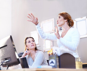Obraz premium Businesswoman gesturing and explaining to coworker at computer