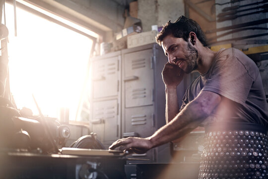 Blacksmith talking on cell phone in forge