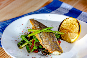 Grilled spicy fish served with asparagus and green beans.Colorful food art composition on plate.