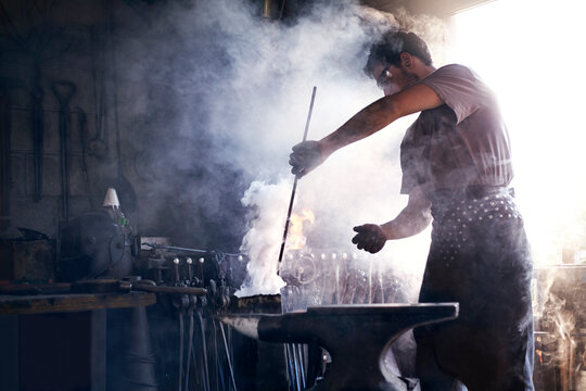 Blacksmith heating iron tool in forge