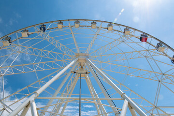 A tall Ferris wheel in the park against a blue sky