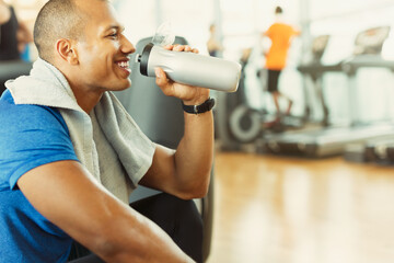 Smiling man drinking water at gym