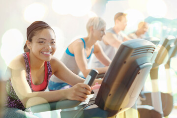 Portrait smiling woman riding exercise bike at gym