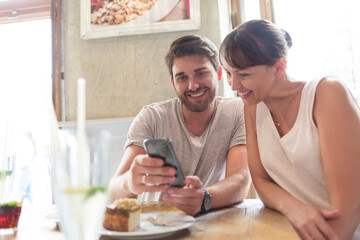 Obraz na płótnie Canvas Couple texting with cell phone at cafe table