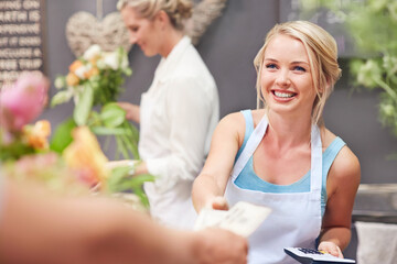 Smiling florist being paid by customer in flower shop