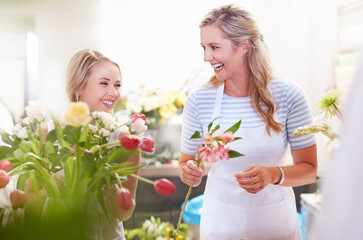 Fototapeta na wymiar Laughing florists arranging bouquet in flower shop