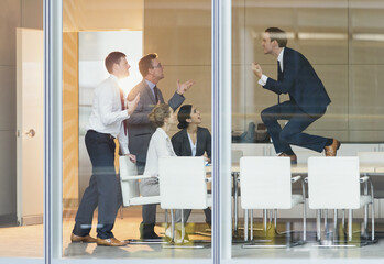 Exuberant businessman gesturing with fists on top of conference table