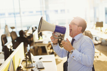 Exuberant businessman shouting into megaphone in office