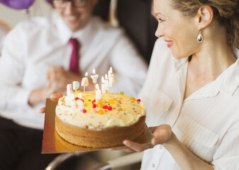 Smiling businesswoman holding birthday cake with candles