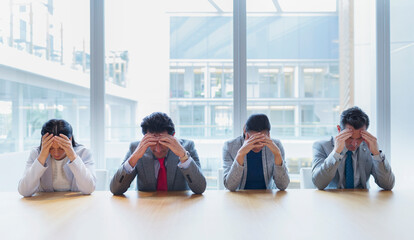 Stressed business people with heads in hands at conference table