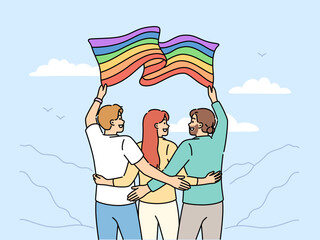 Fototapeta premium Group of people with LGBT flag travel with pride community and admire beautiful nature. Two man and woman hugging holding lgbt banner calling to be more tolerant towards lesbians or transgenders