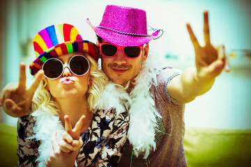 Portrait playful couple in costume sunglasses hats gesturing peace sign