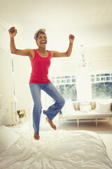 Fototapeta na wymiar Playful enthusiastic mature woman jumping on bed