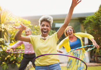 Portrait playful mature adults spinning with plastic hoops in garden