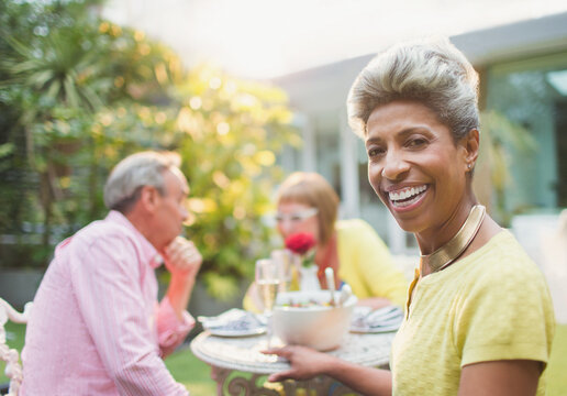 Portrait smiling mature woman enjoying lunch with friends in garden