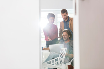 Creative business people sharing laptop in office meeting