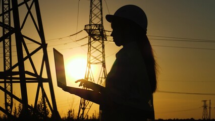 silhouette electrical engineer, work laptop sunset, electric tower, writes down data, construction,...