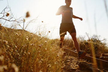 Man running down sunny trail
