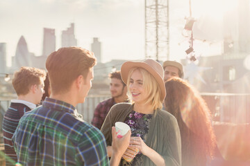 Young man and woman drinking and talking at rooftop party