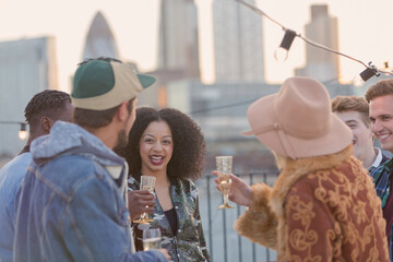 Fototapeta premium Young adult friends drinking champagne at rooftop party
