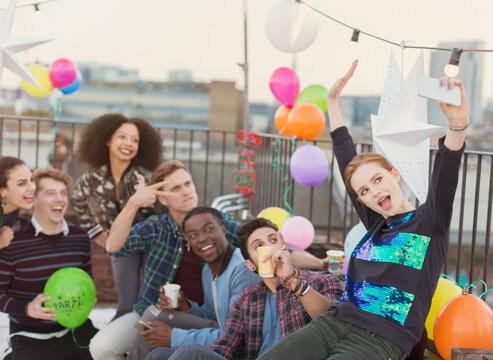 Enthusiastic young adult friends taking selfie at rooftop party