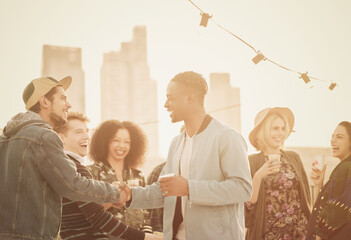 Young adult friends handshaking at rooftop party