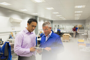 Manager and engineer looking at clipboard in steel factory office - obrazy, fototapety, plakaty