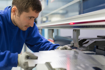 Worker operating laser cutter in steel factory - obrazy, fototapety, plakaty