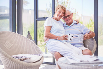 Portrait smiling senior couple drinking coffee on sun porch