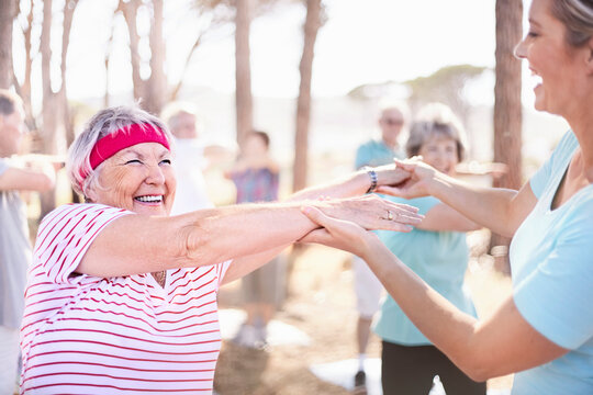 Yoga instructor guiding senior woman in park