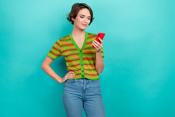 Photo of shiny adorable lady wear striped cardigan typing sms modern gadget empty space isolated teal color background