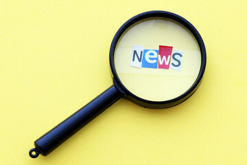 The word NEWS arranged from cut letters under a black magnifying glass