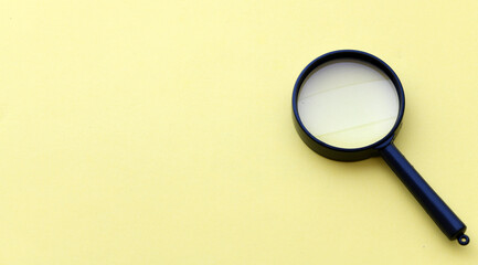 Black magnifier on a yellow background.