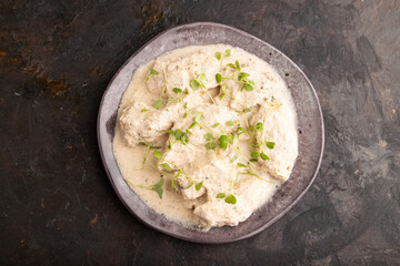 Stewed chicken fillets with coconut milk sauce and rucola microgreen. top view, close up.