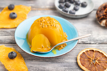 Mango and passion fruit jelly with blueberry on gray wooden, side view, selective focus.