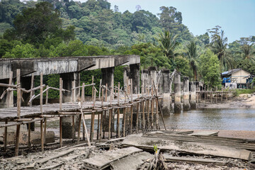 Fototapeta na wymiar Destroyed concrete and bamboo bridge across the river to the Aboriginal village.