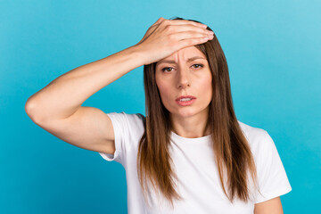 Fototapeta na wymiar Portrait of a beautiful upset young woman standing isolated over blue background suffering from headache