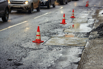 Traffic cones separated the repaired section of the asphalt road from traffic. Repair of damaged...