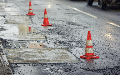 Traffic cones and asphalt pavement patching, removing pothole. Road repair work. Repair damaged...