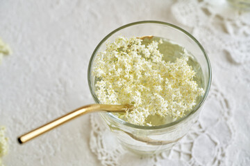 Fresh elder flowers in a glass of lemonade with a metal drinking straw