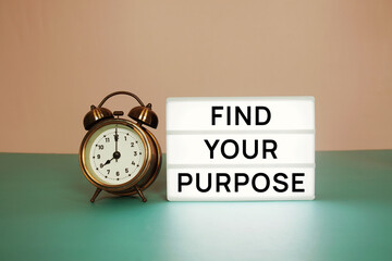 Find Your Purpose text message on paper card with wooden easel and alarm clock