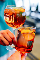 hands holding and clinking glasses cocktails in restaurant