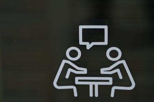 sign with two people sitting at the table talking. detail.