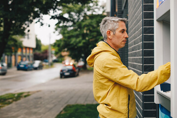 Mid-adult man withdrawing money from ATM.