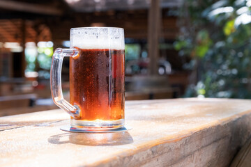 Cold craft beer mug on summer bar wooden table