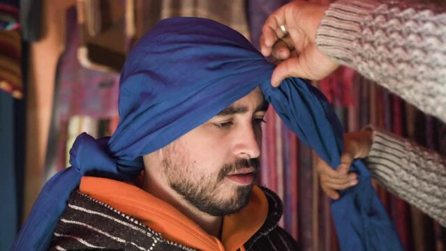 A person puts a berber turban to someone