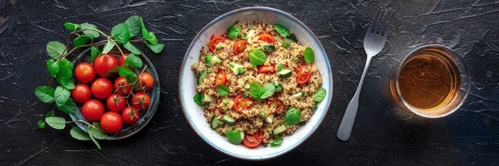 Quinoa tabbouleh salad in a bowl panorama, a healthy dinner with tomatoes and mint, with a drink,...