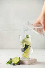 Detox infused water in glass. Refreshing summer homemade cocktail with fruit, berries and citrus