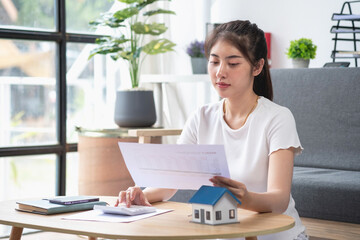 woman sitting on cozy sofa and planning and calculate expense and mortgage with calculator and home on desk, insurance and budget of residential, loan and residence, business and property concept.