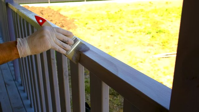 Painting the wooden deck in grey. Selective focus.